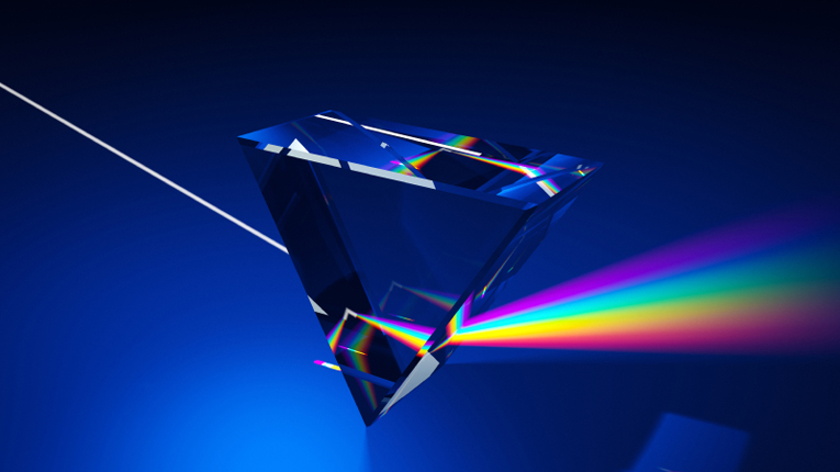 A beam of white light passes through a glass prism and disperses into a rainbow spectrum against a blue background.